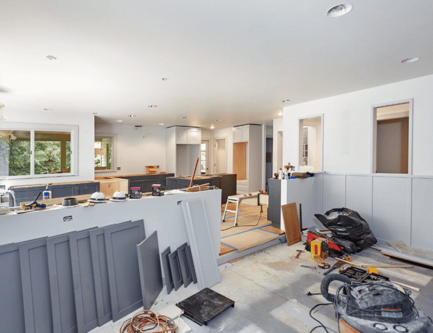 Open-plan home interior under renovation with drywall, tools and materials