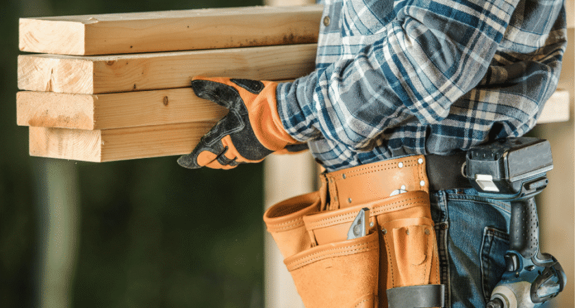 Contractor with a tool belt carrying lumber on a remodeling job