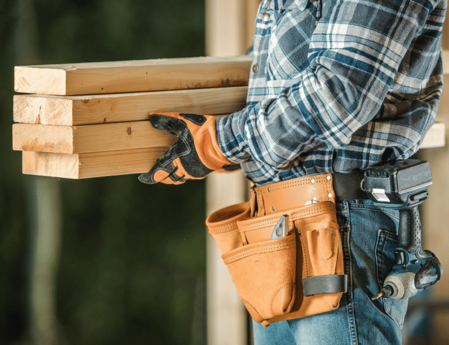 Contractor with a tool belt carrying lumber on a remodeling job